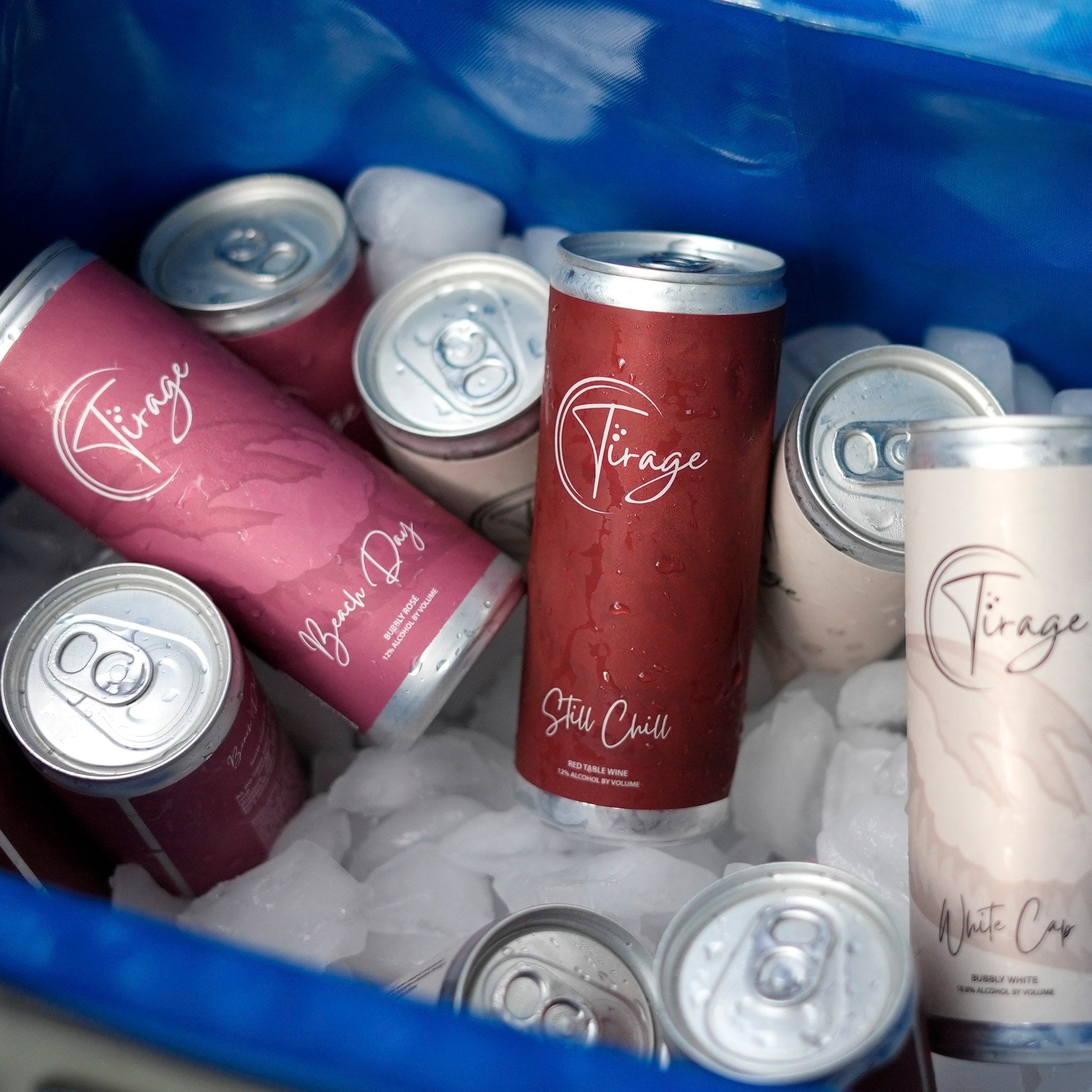 Assorted Tirage wine cans on ice in blue cooler, featuring Beach Day rosé, Still Chill red, and White Cap bubbly white